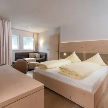 Widderstein Modernes Hotelzimmer mit Holzmöbeln, Doppelbett, Fernseher und Sitzecke am Fenster